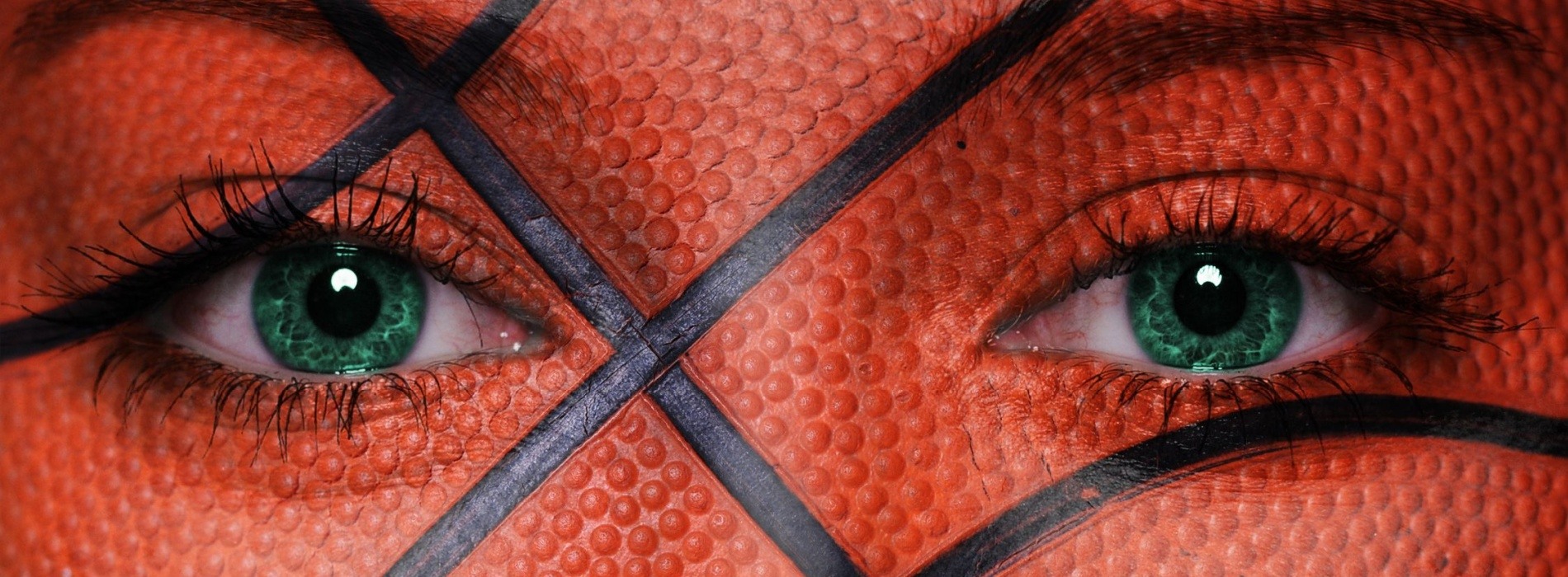 woman's face with green eyes and basketball facepaint