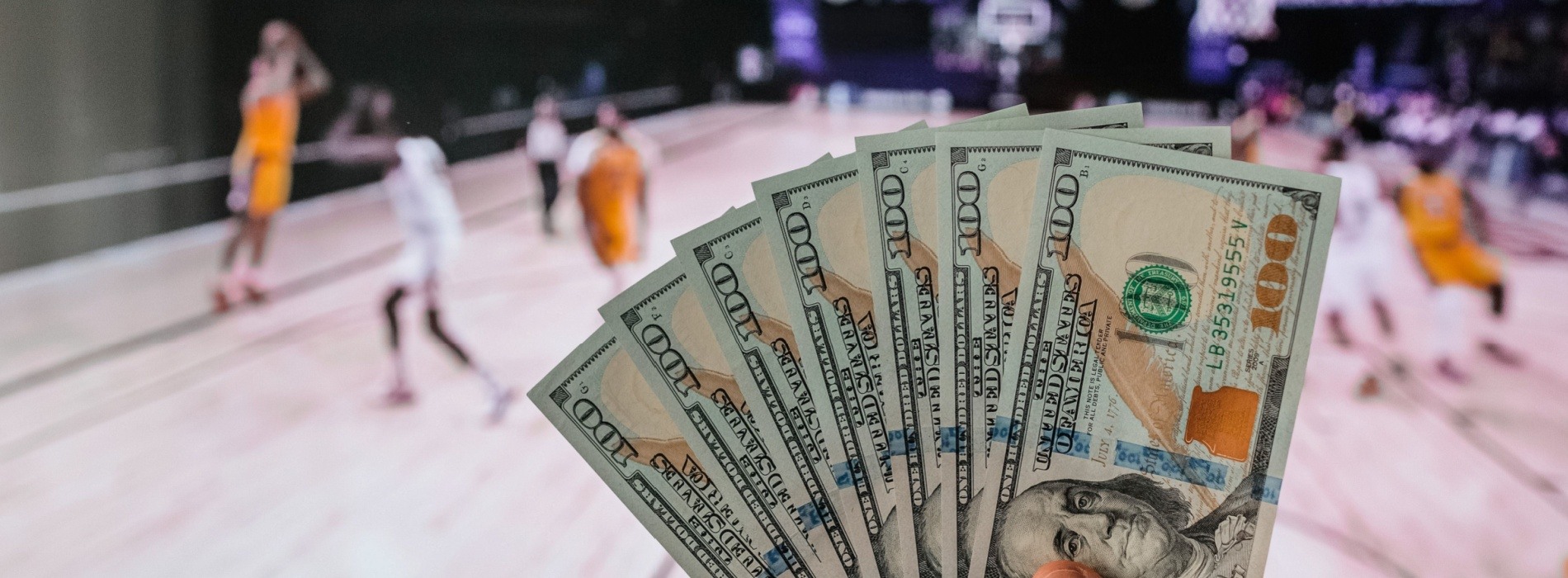 money fan held in front of basketball game