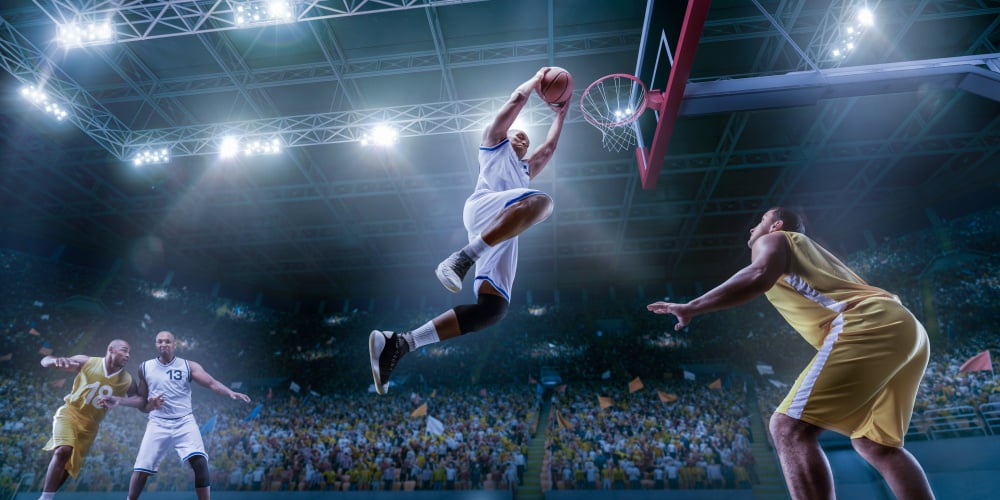 Basketball players on big professional arena during the game. Basketball player makes slam dunk. Bottom view